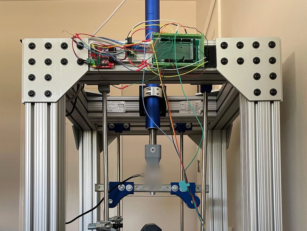 Custom biomechanics test machine built from aluminium extrusion, with the specimen obscured